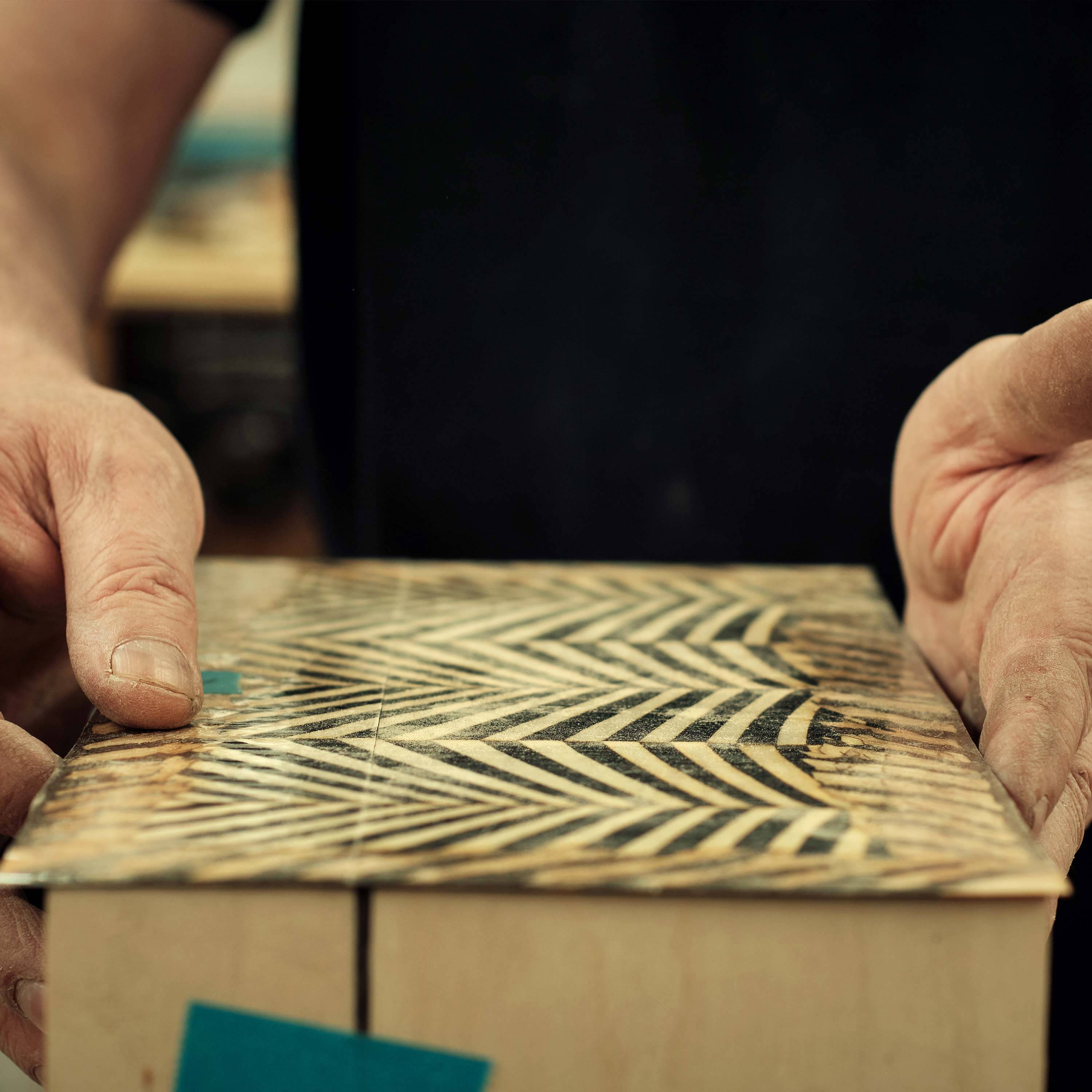 A master joiner applying wood veneer design to a poker box exterior